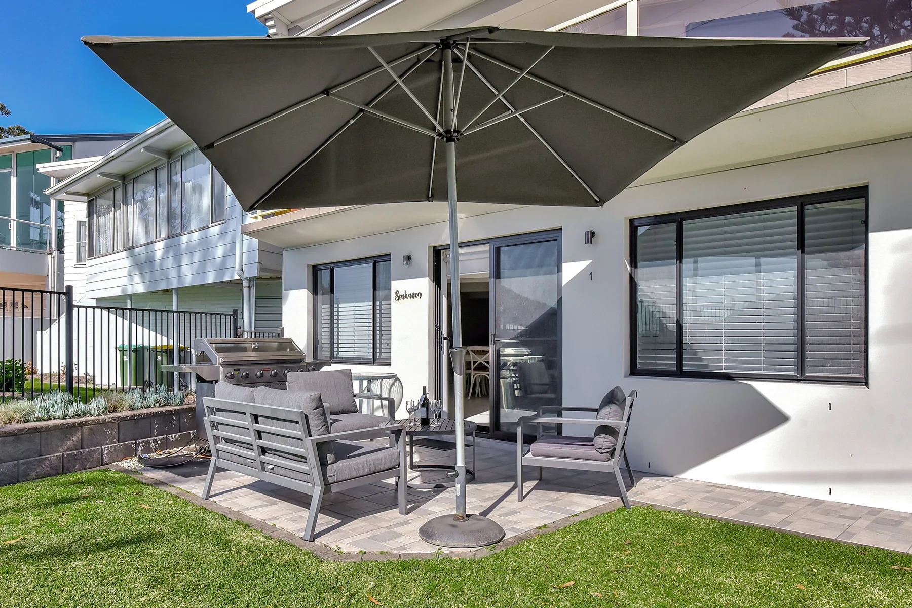 Outdoor patio seating beneath a large umbrella beside a modern building.