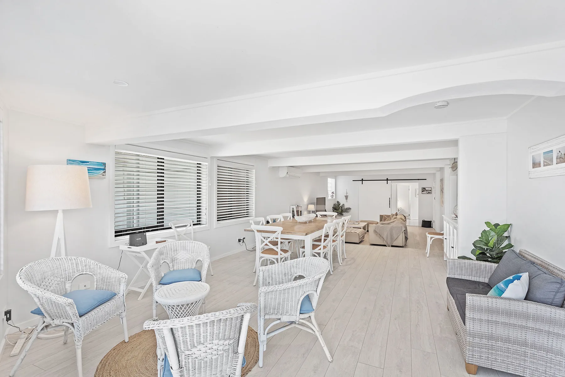 A bright living and dining area with white seating and large windows.