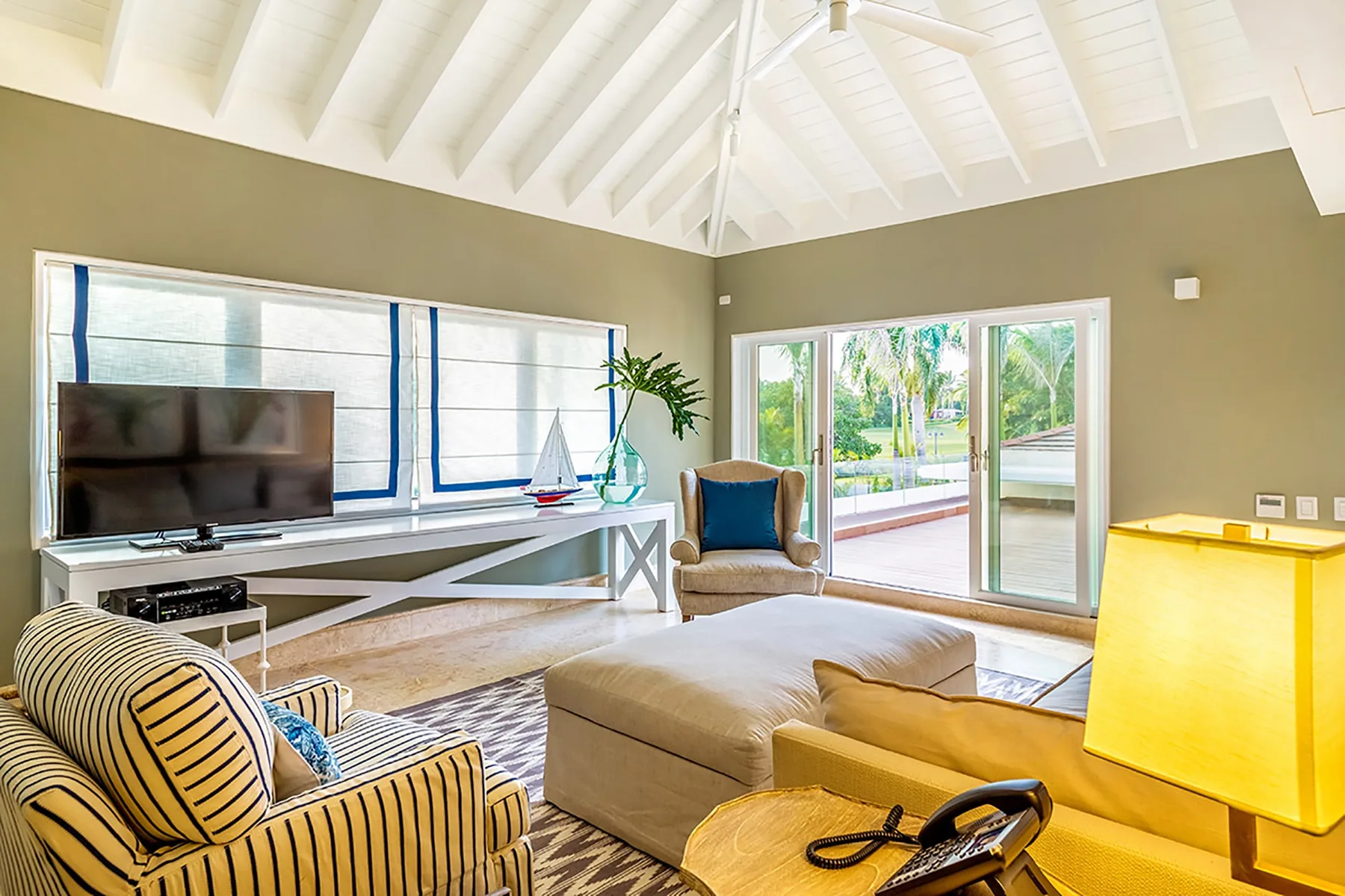 Una sala luminosa con asientos, un televisor y puertas de vidrio que dan a un patio.
