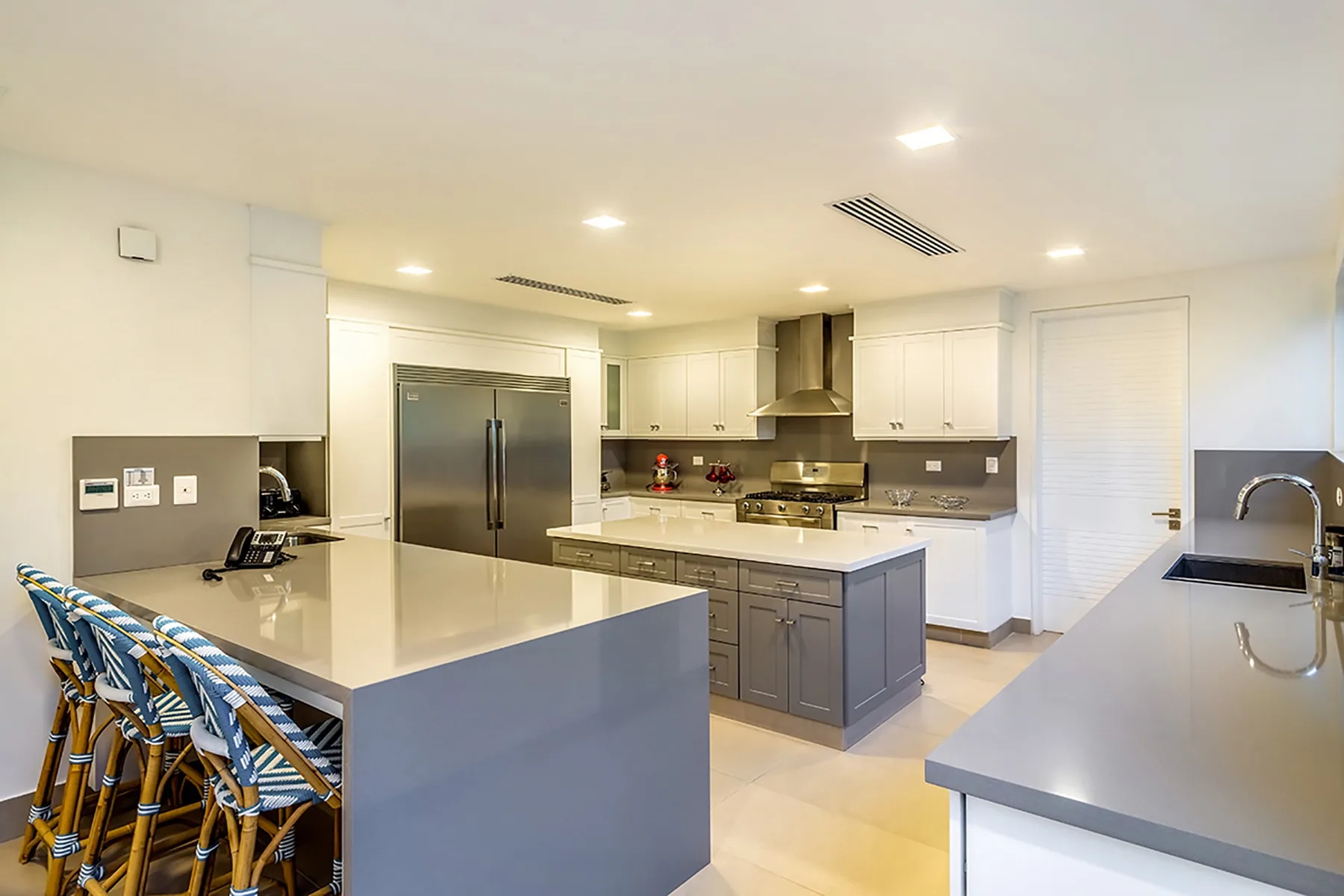 A bright kitchen with a central island, countertop seating, and stainless steel appliances.