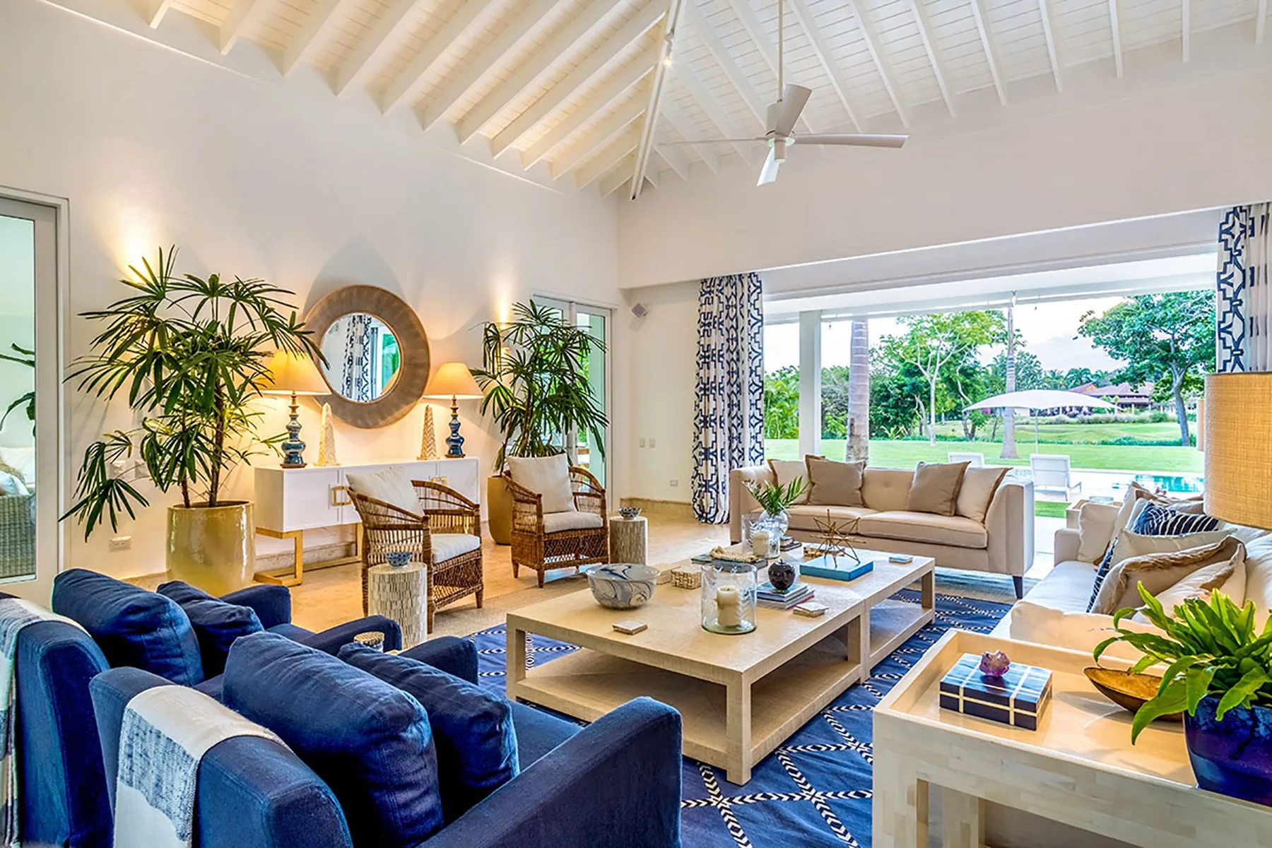 A bright living room opens onto a garden through wide glass doors.