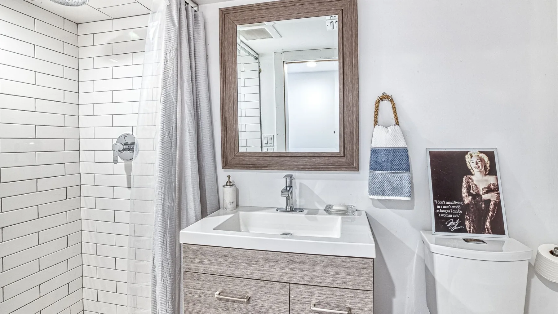 Un baño luminoso con una ducha de azulejos y un lavabo con mueble.