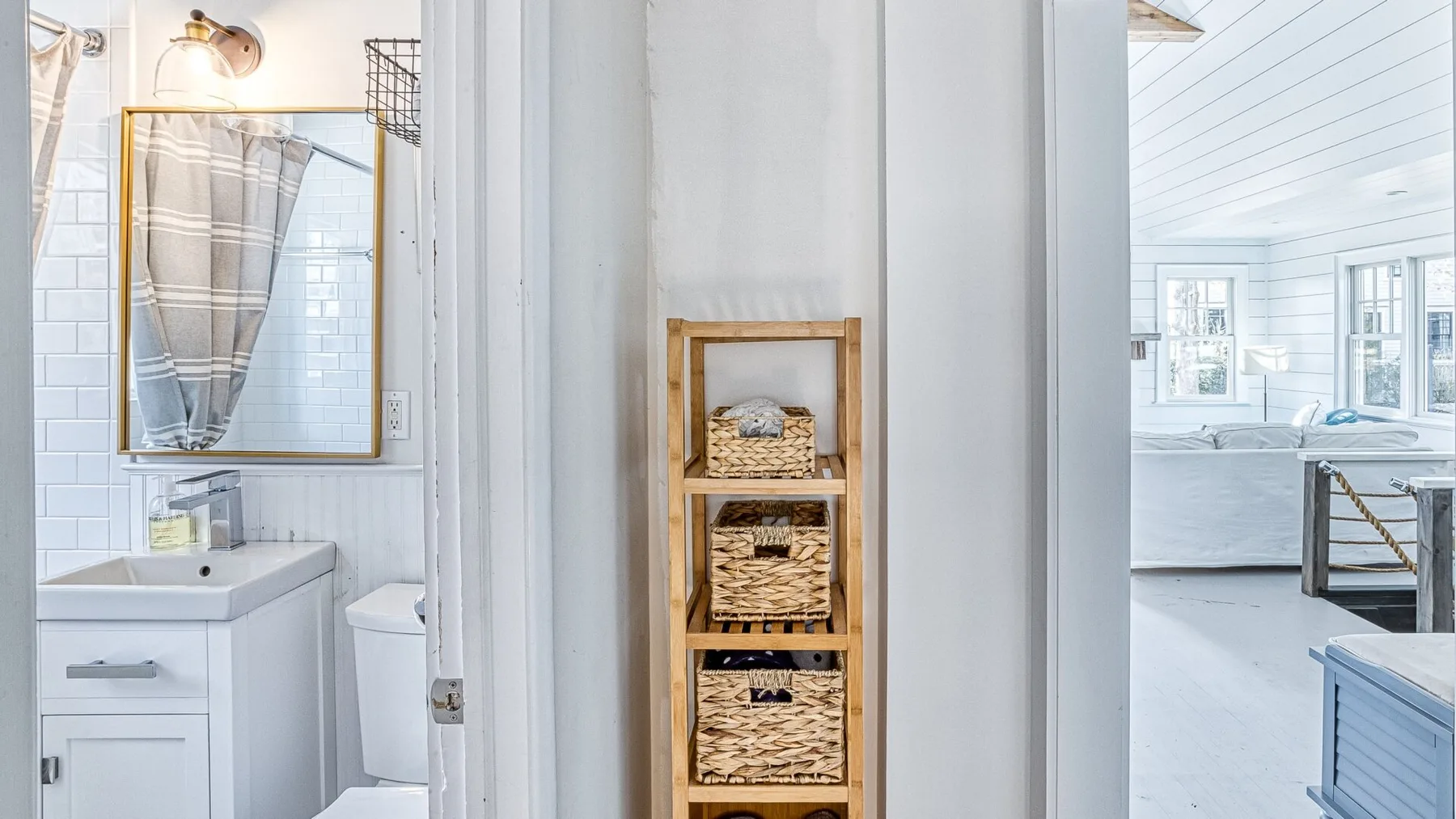 Se ve un lavabo de baño y una ducha junto a una estrecha estantería de madera.