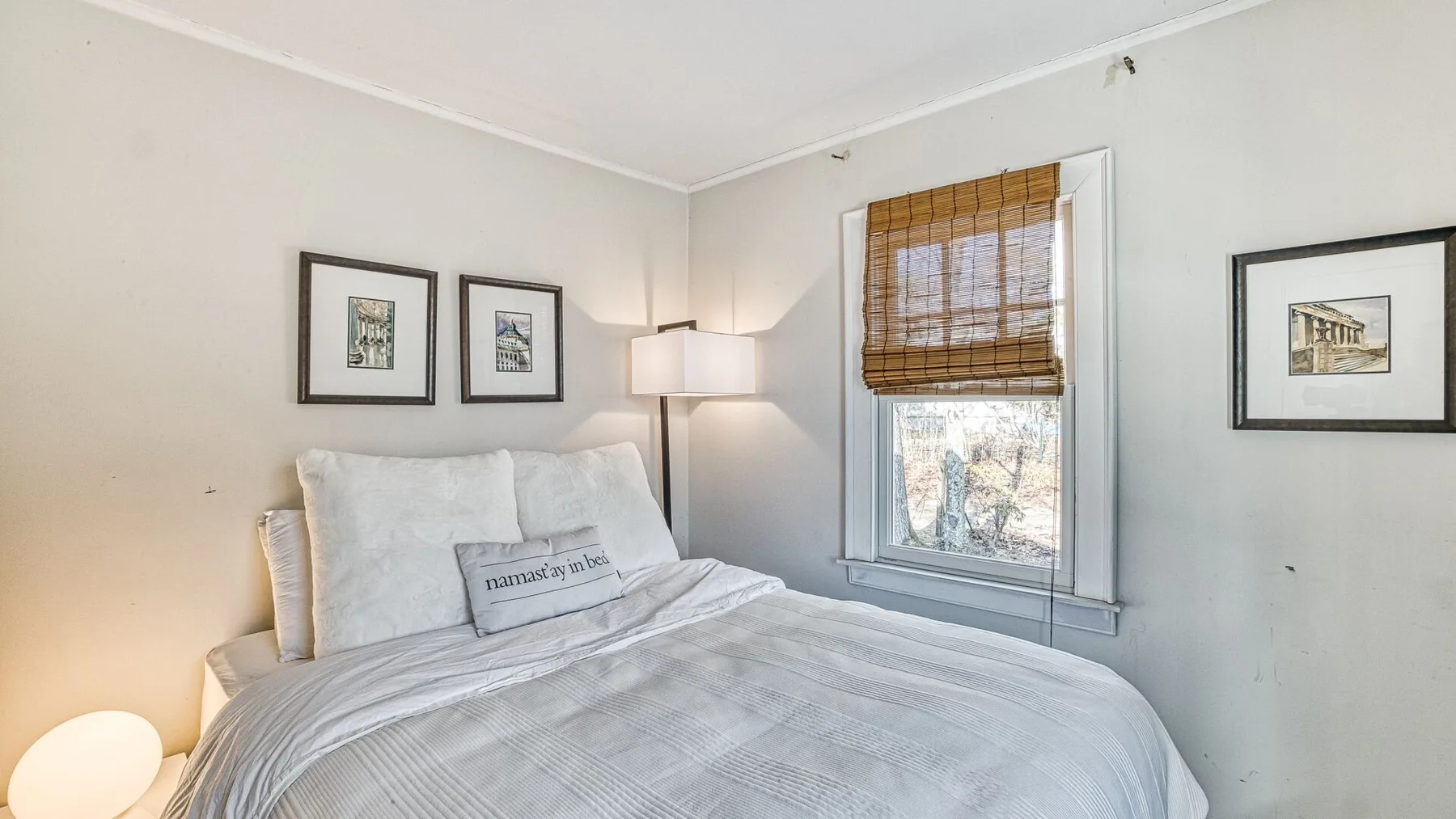Un dormitorio luminoso con una cama grande y una ventana con persianas tejidas.