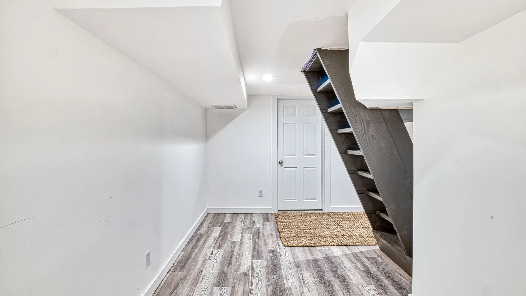 Una pequeña habitación en el sótano con una puerta blanca y estantes empotrados.