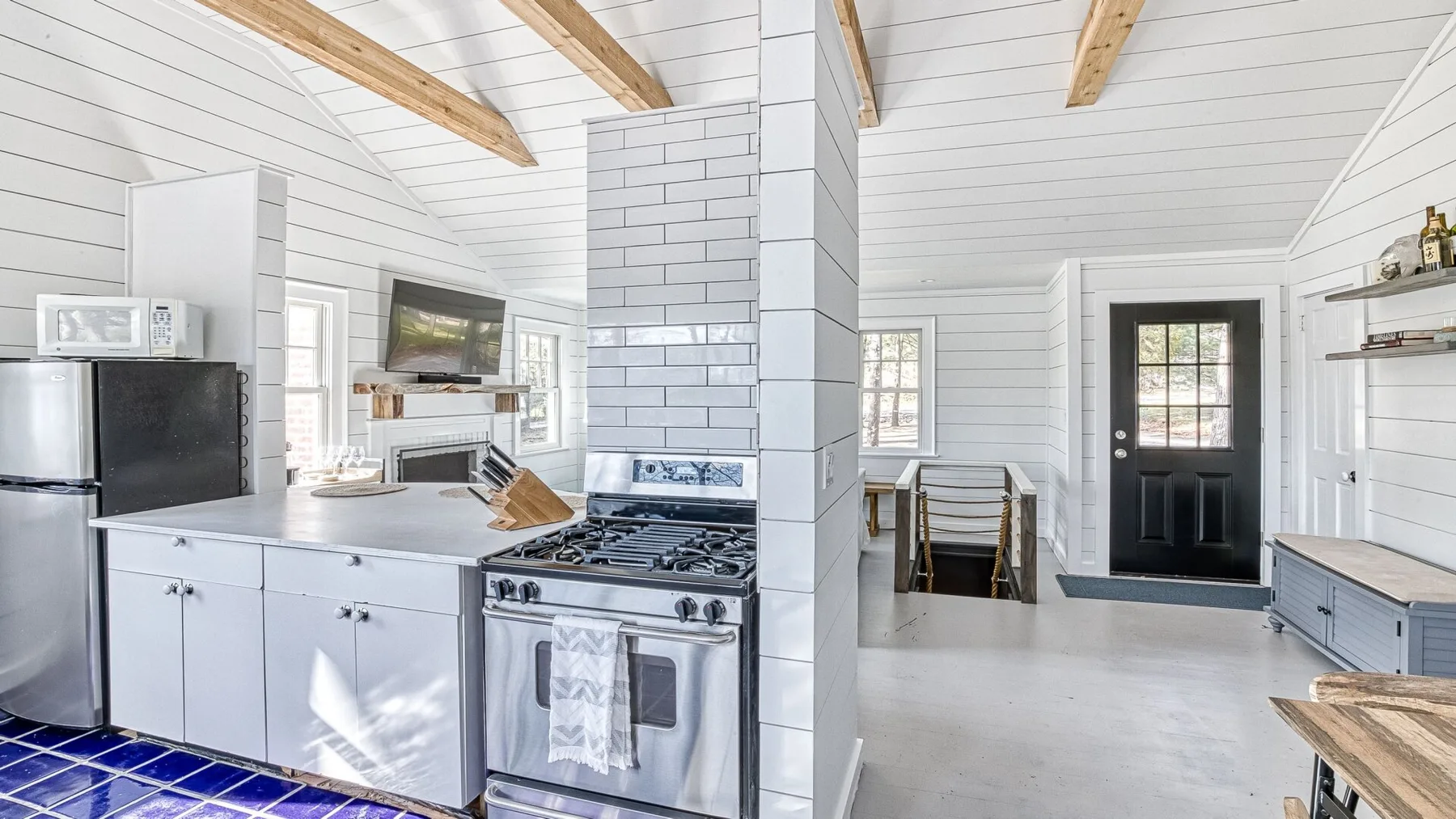 Una cocina luminosa con gabinetes blancos, una estufa y una columna central revestida de azulejos.