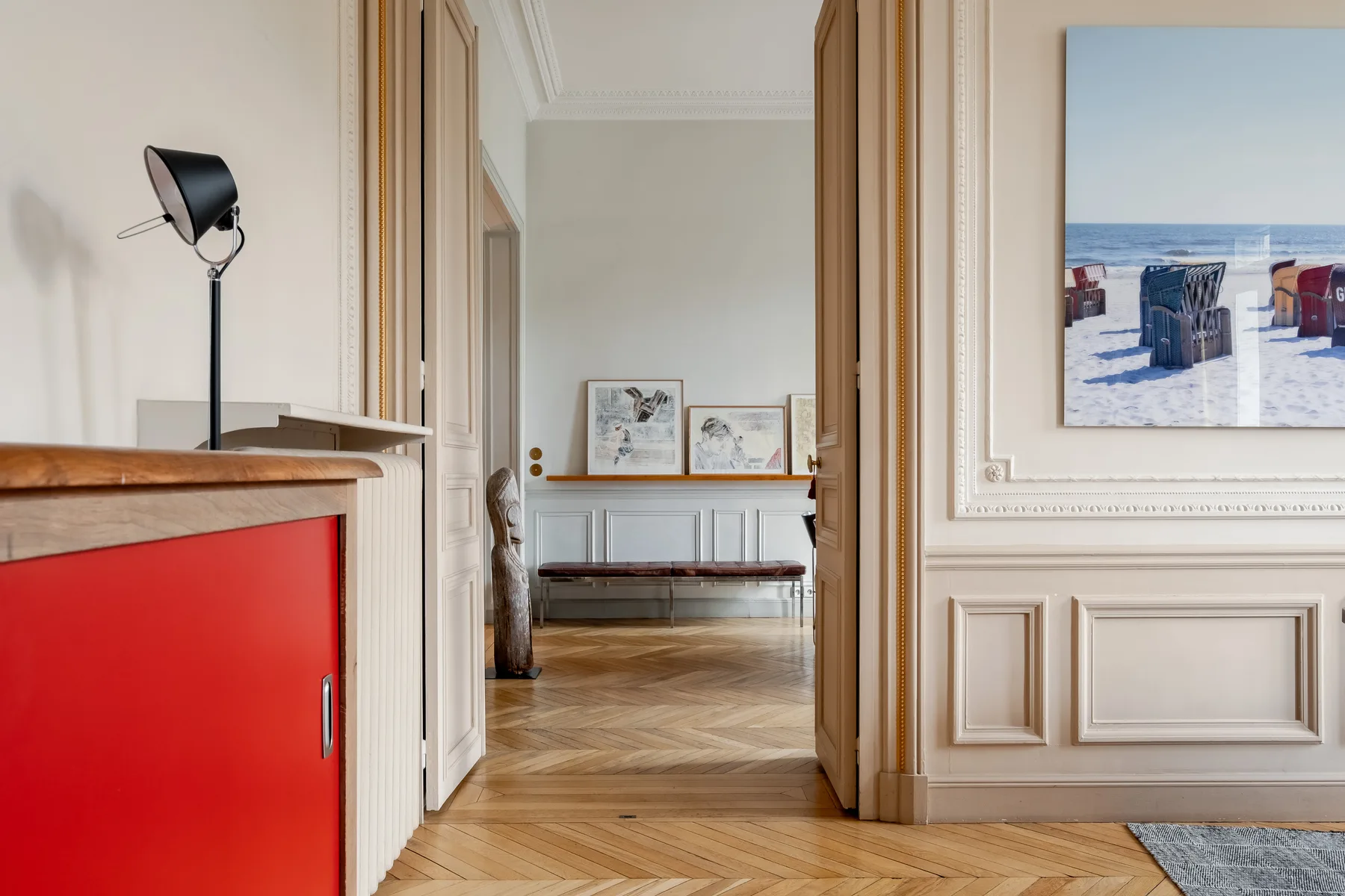 A bright interior hallway opens into a room with a bench and framed artwork.