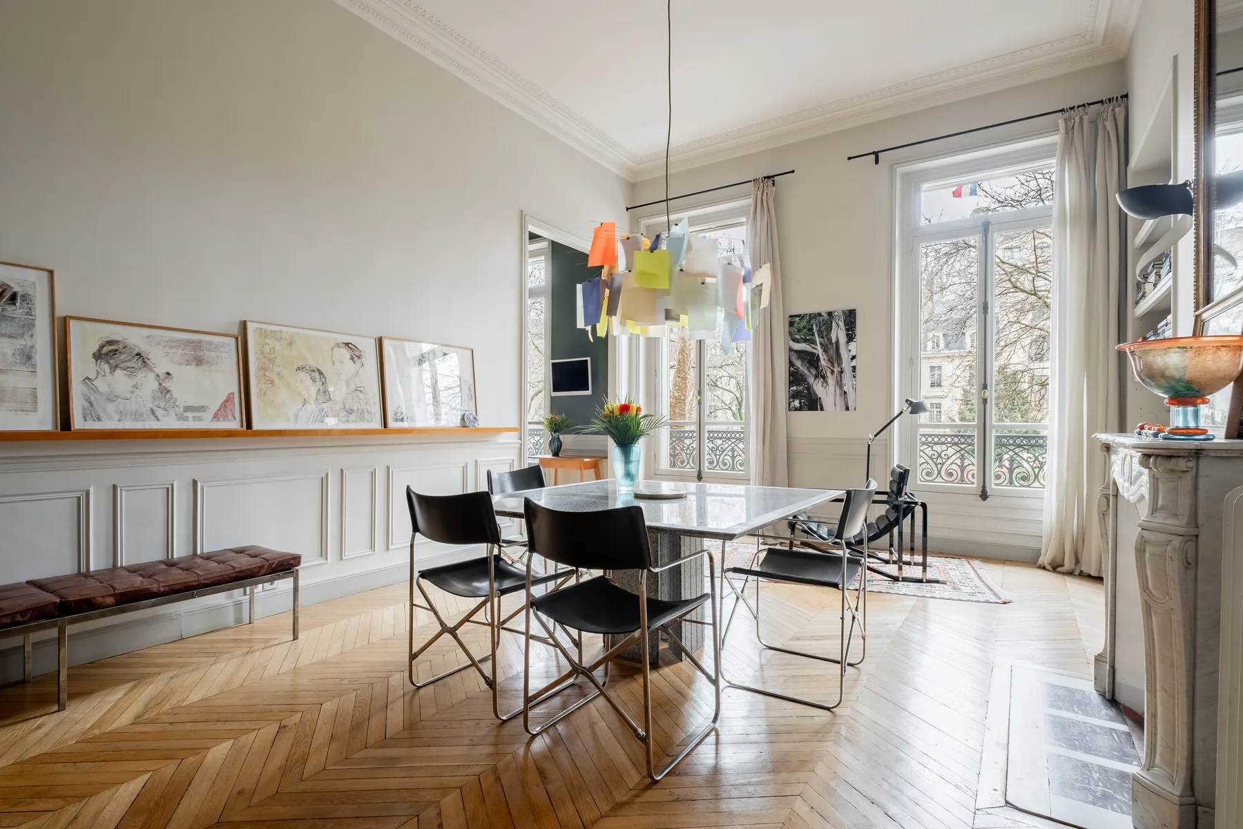 Un comedor luminoso con una mesa, asientos y ventanas altas.