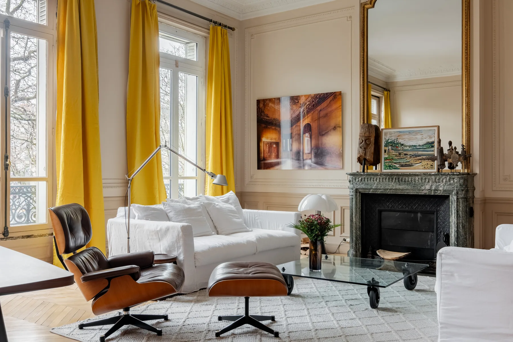 A bright living room with white seating, yellow curtains, and a fireplace.