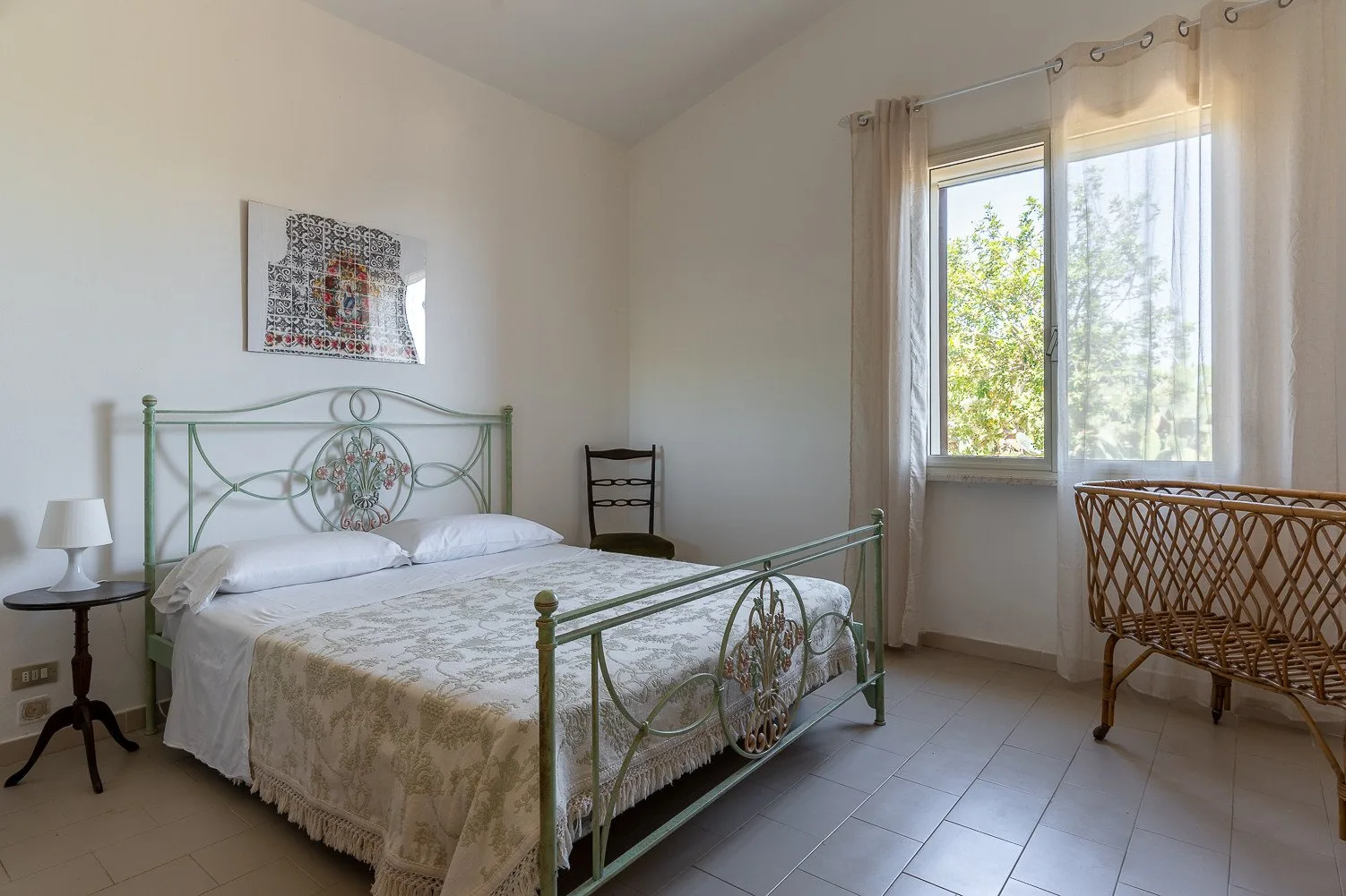 Un dormitorio con una cama de metal bajo una ventana grande.