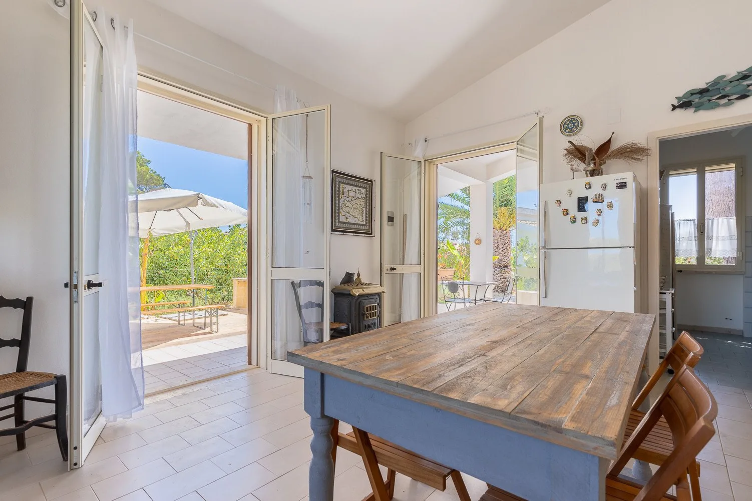 Un comedor luminoso con una mesa de madera y puertas abiertas a un patio.