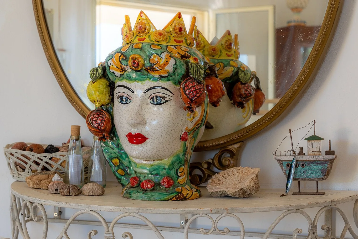 Una cabeza decorativa de cerámica está sobre un estante en una exposición interior.