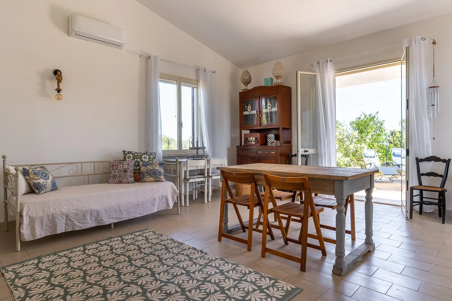 Una luminosa zona de comedor y estar cuenta con una mesa de madera y un diván.