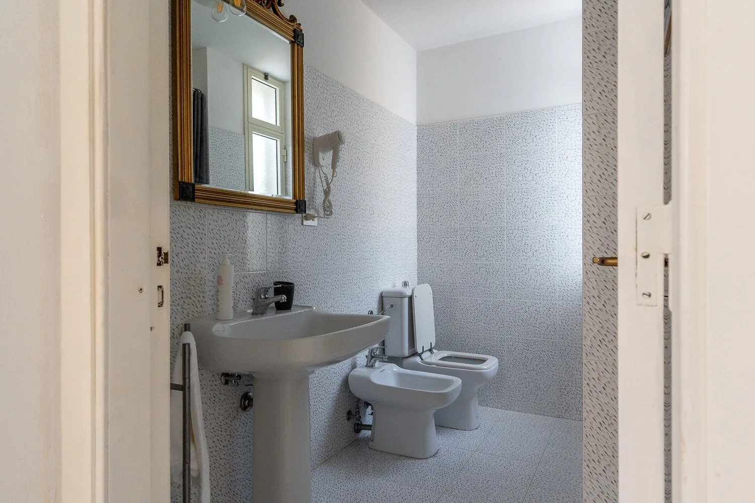 Un baño con azulejos, lavabo, espejo, inodoro y bidé.