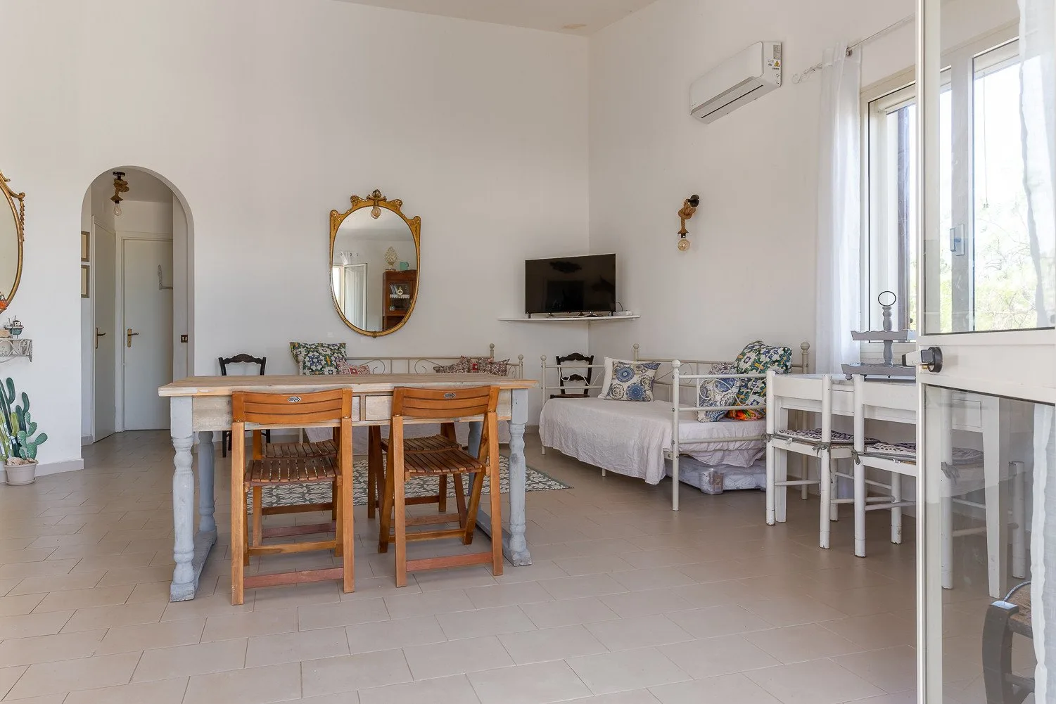 Una luminosa sala de estar y comedor con una mesa de madera, asientos y un televisor.