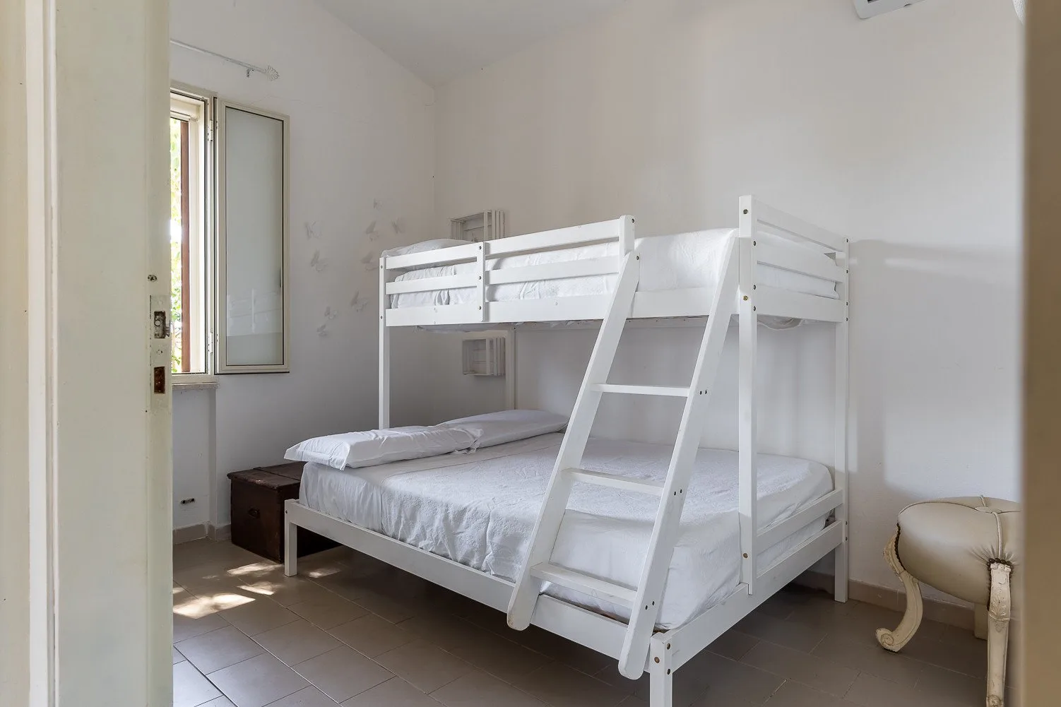 Un dormitorio con una litera blanca y una ventana.