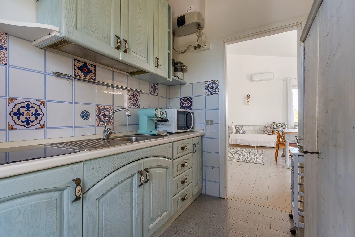 Una cocina con gabinetes claros, un salpicadero de azulejos y vista a un dormitorio.
