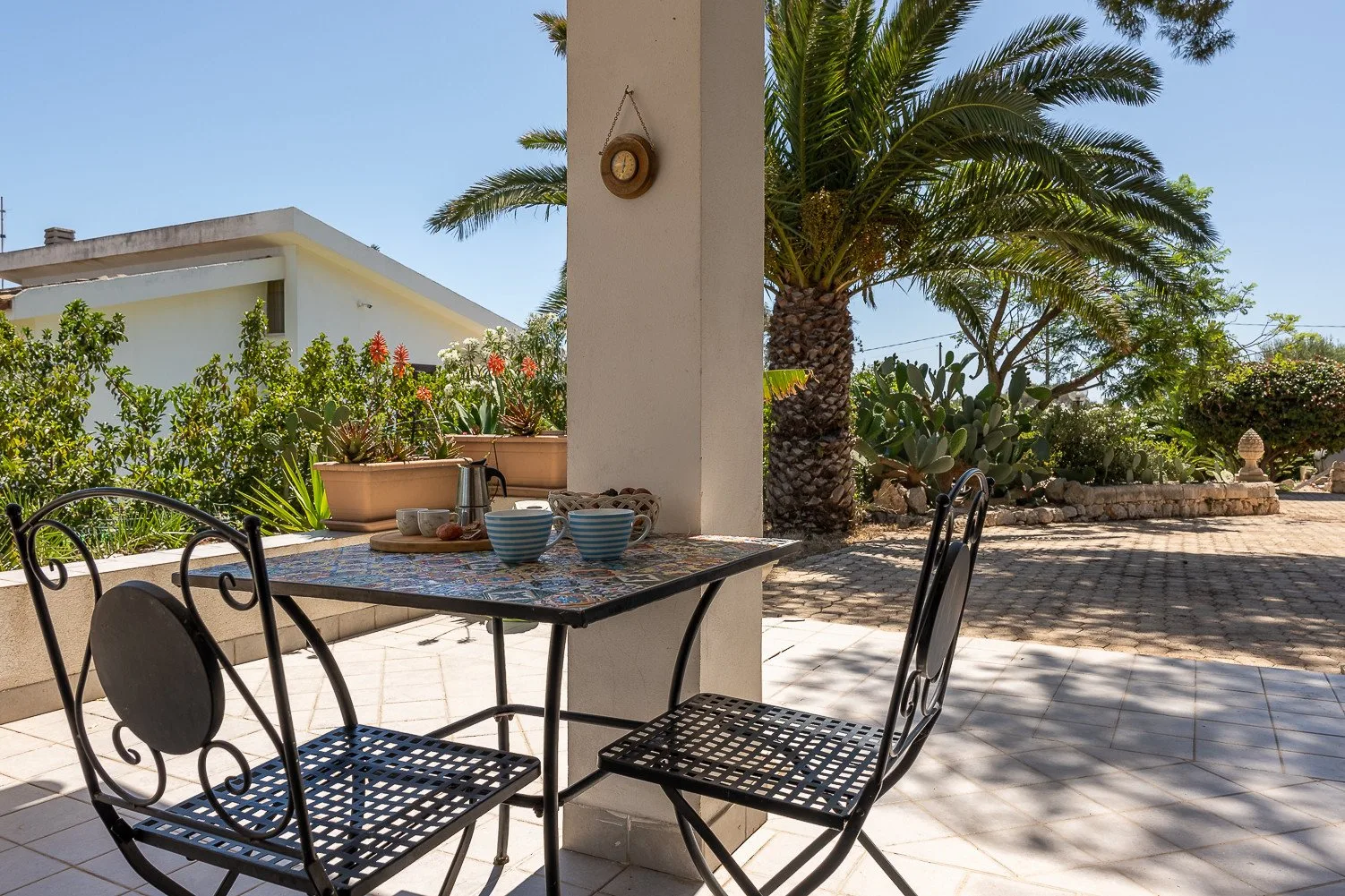 Un patio al aire libre con una mesa y sillas junto a una palmera.