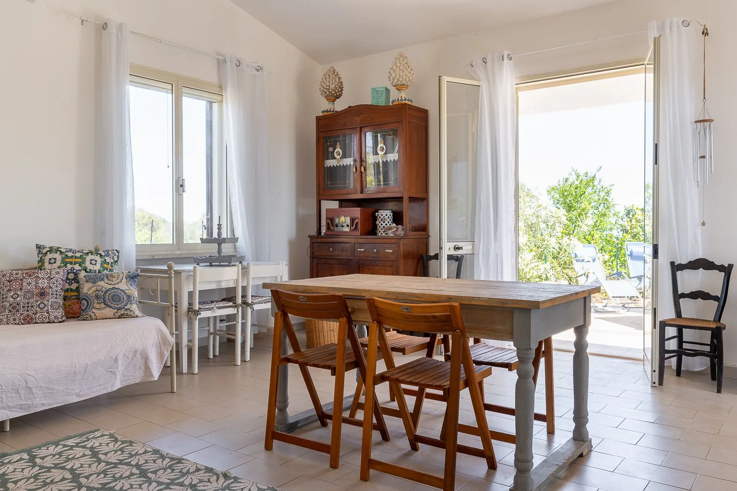 Comedor con una mesa de madera y asientos junto a una puerta abierta al patio.