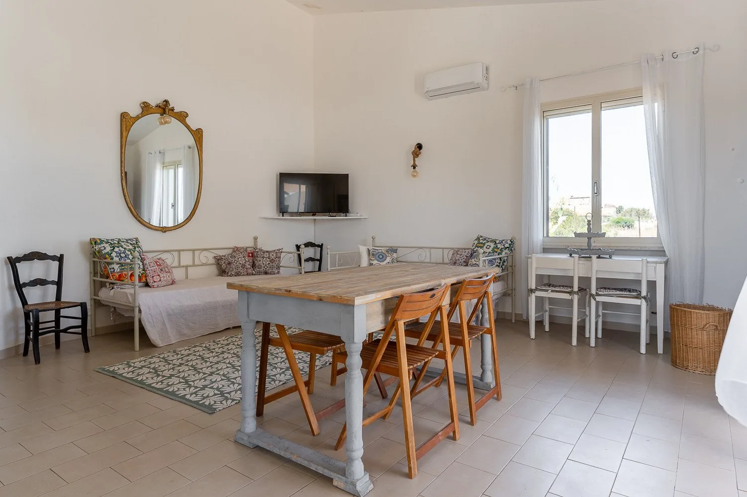 Una luminosa zona de comedor y estar con una mesa de madera y asientos junto a la ventana.