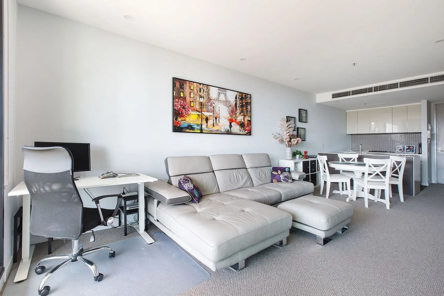 A living and dining area with a sectional seating area and a desk.