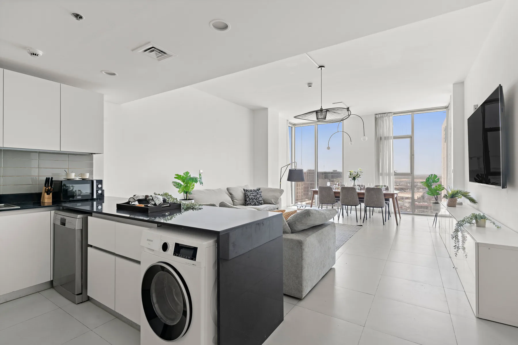 Un espacio diáfano y luminoso reúne cocina, zona de estar y mesa de comedor junto a grandes ventanales.