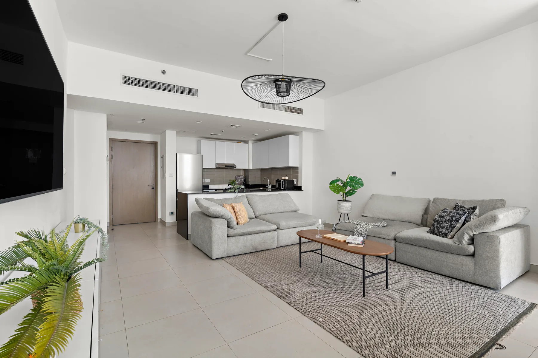 Una sala luminosa con asientos, una mesa de centro y una cocina abierta.