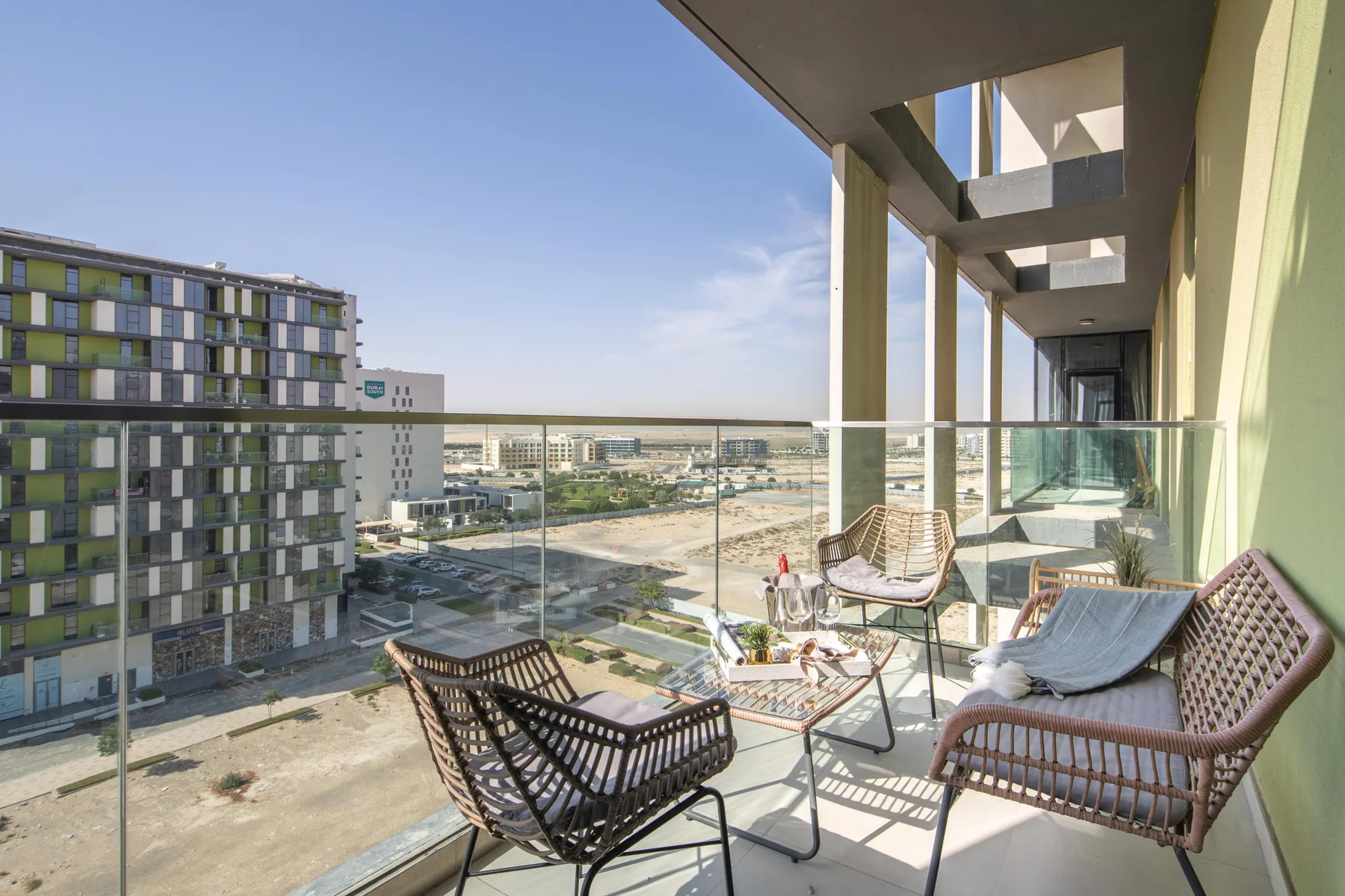 Un balcón con asientos al aire libre y vistas de edificios cercanos.