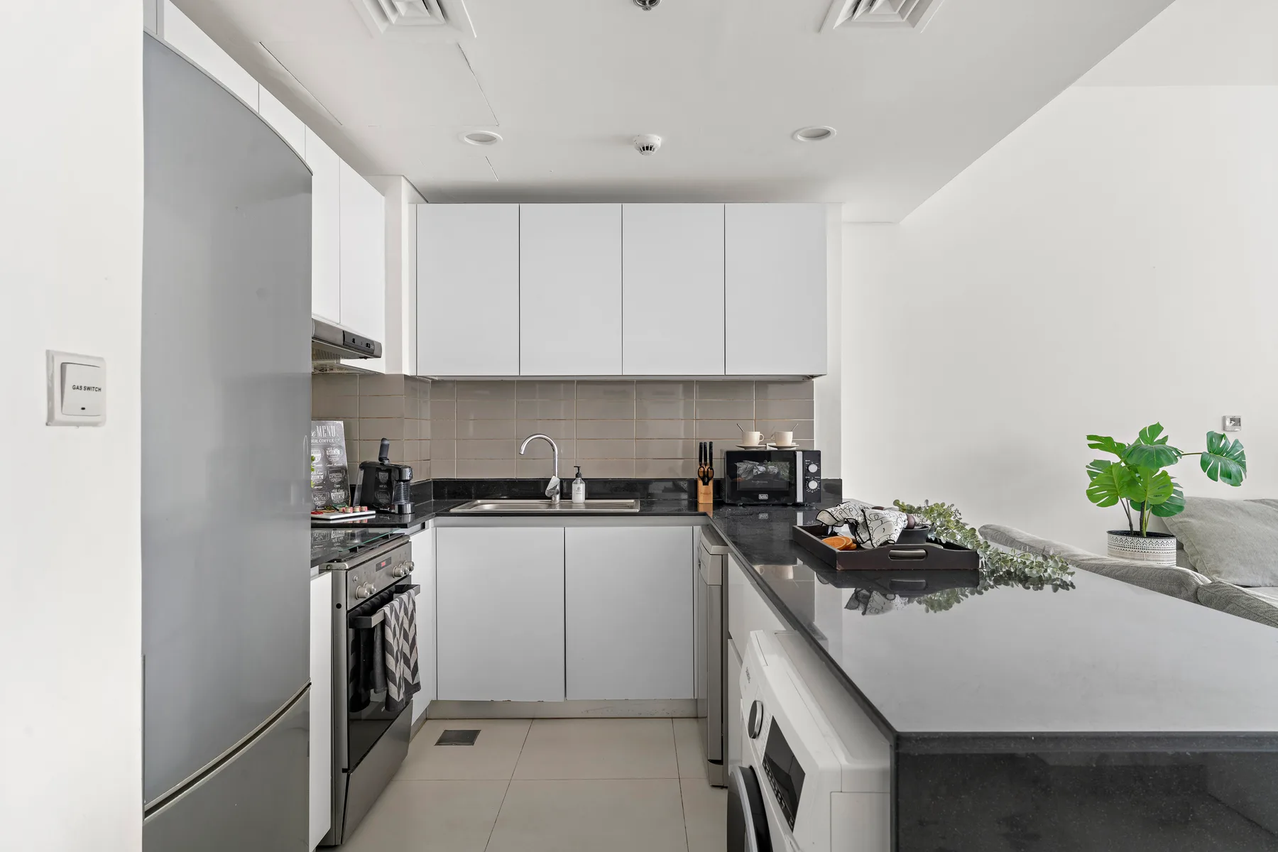 Una cocina moderna y luminosa con gabinetes blancos y una encimera larga.
