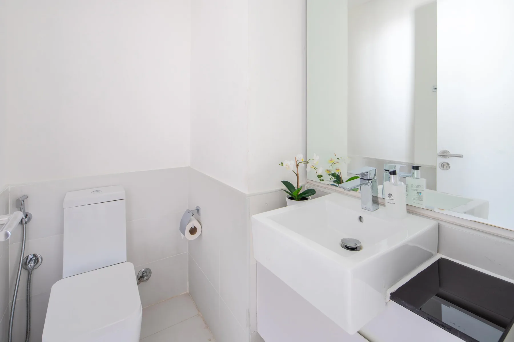 Un baño luminoso con lavabo, espejo e inodoro.