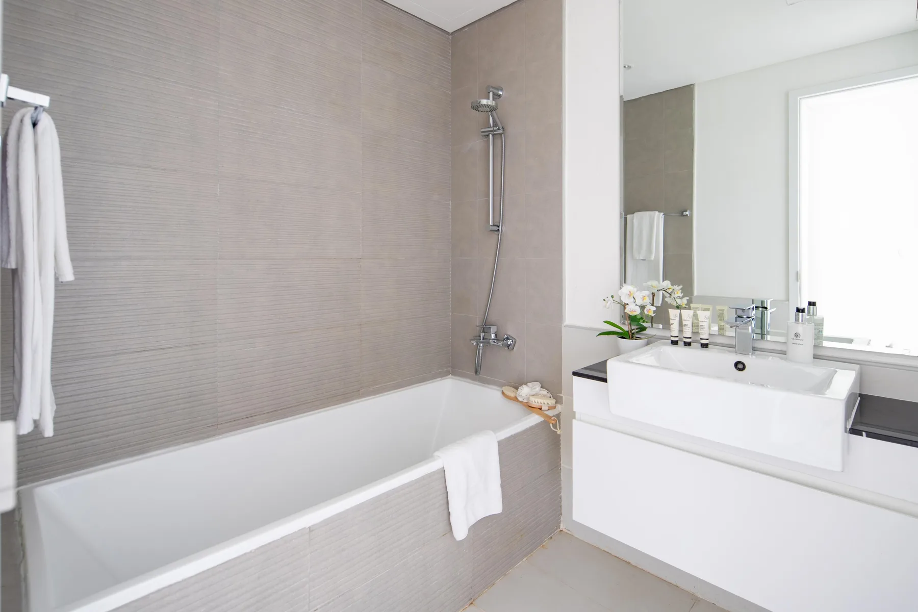 Un baño moderno con bañera y lavabo bajo un espejo grande.