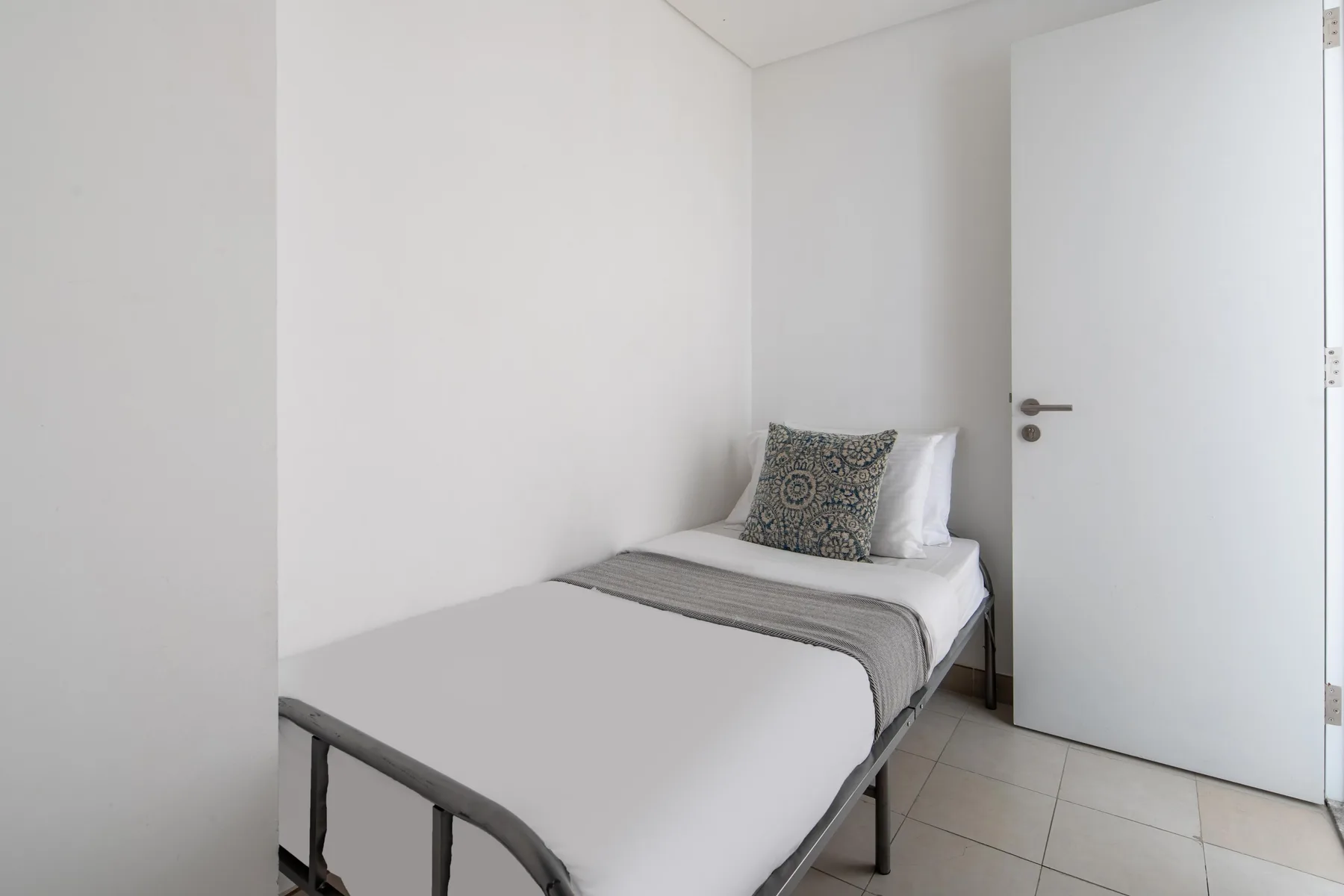 Un dormitorio pequeño con una cama individual y almohadas estampadas.