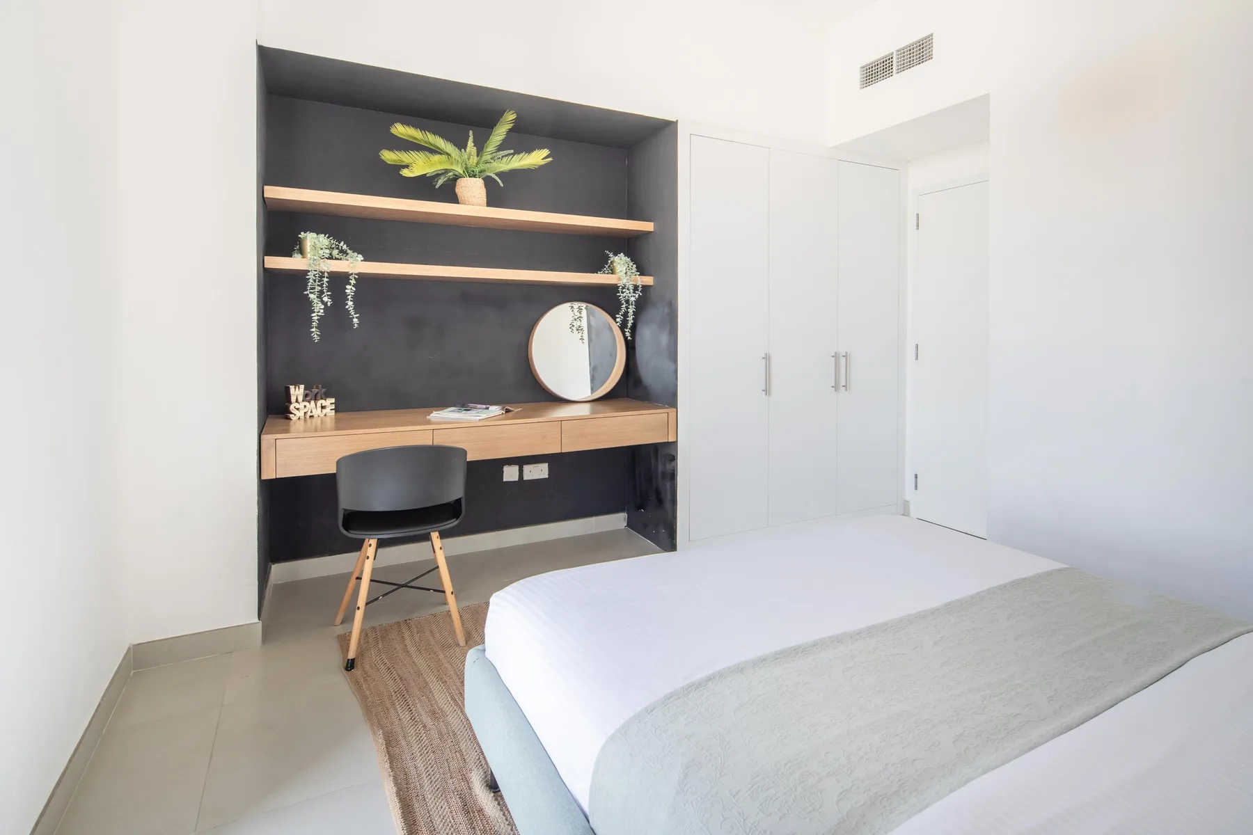 Un dormitorio luminoso con cama, escritorio empotrado y estanterías.