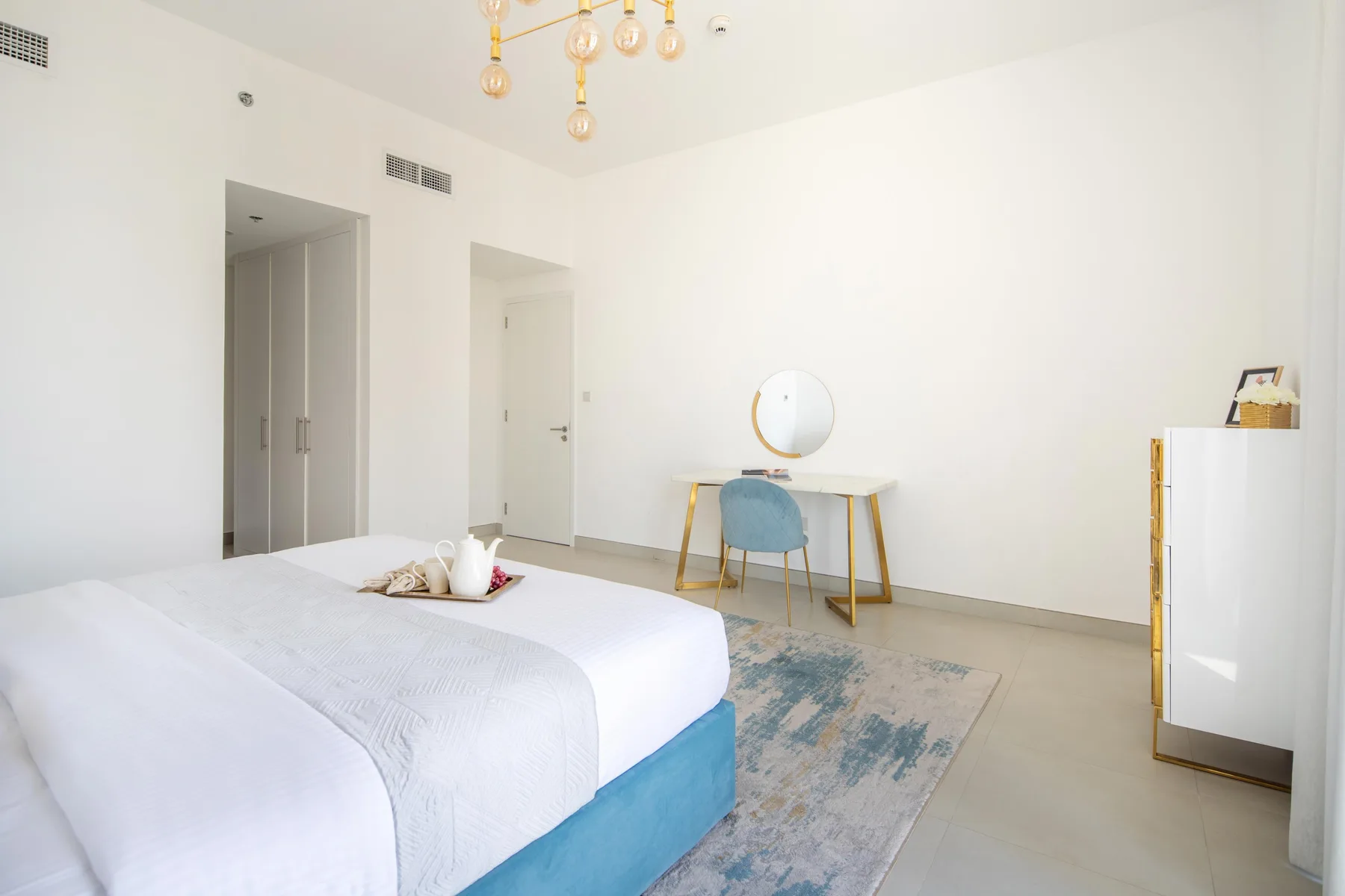 Un dormitorio luminoso con una cama, un escritorio y una silla.