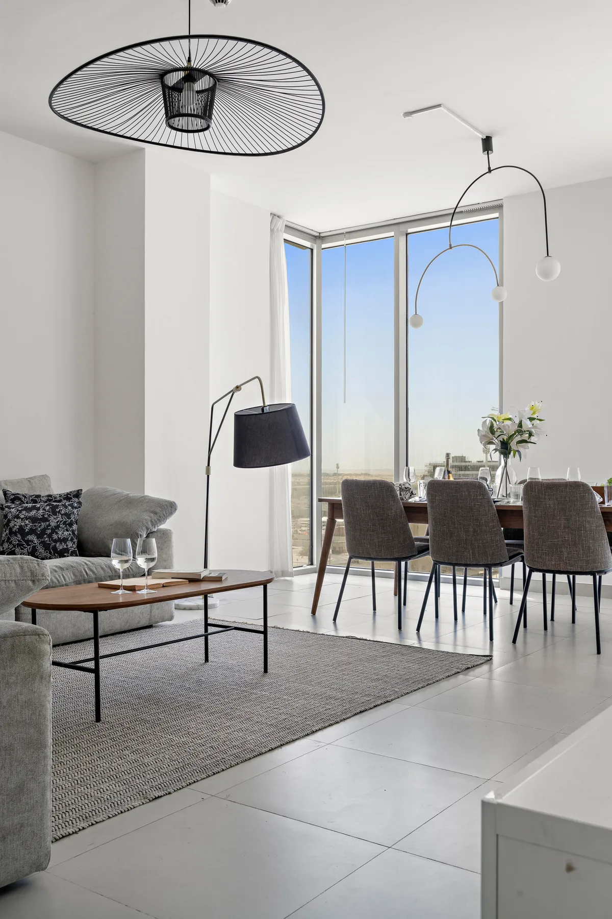 Una luminosa sala de estar y comedor con sofá, mesa y ventanales.