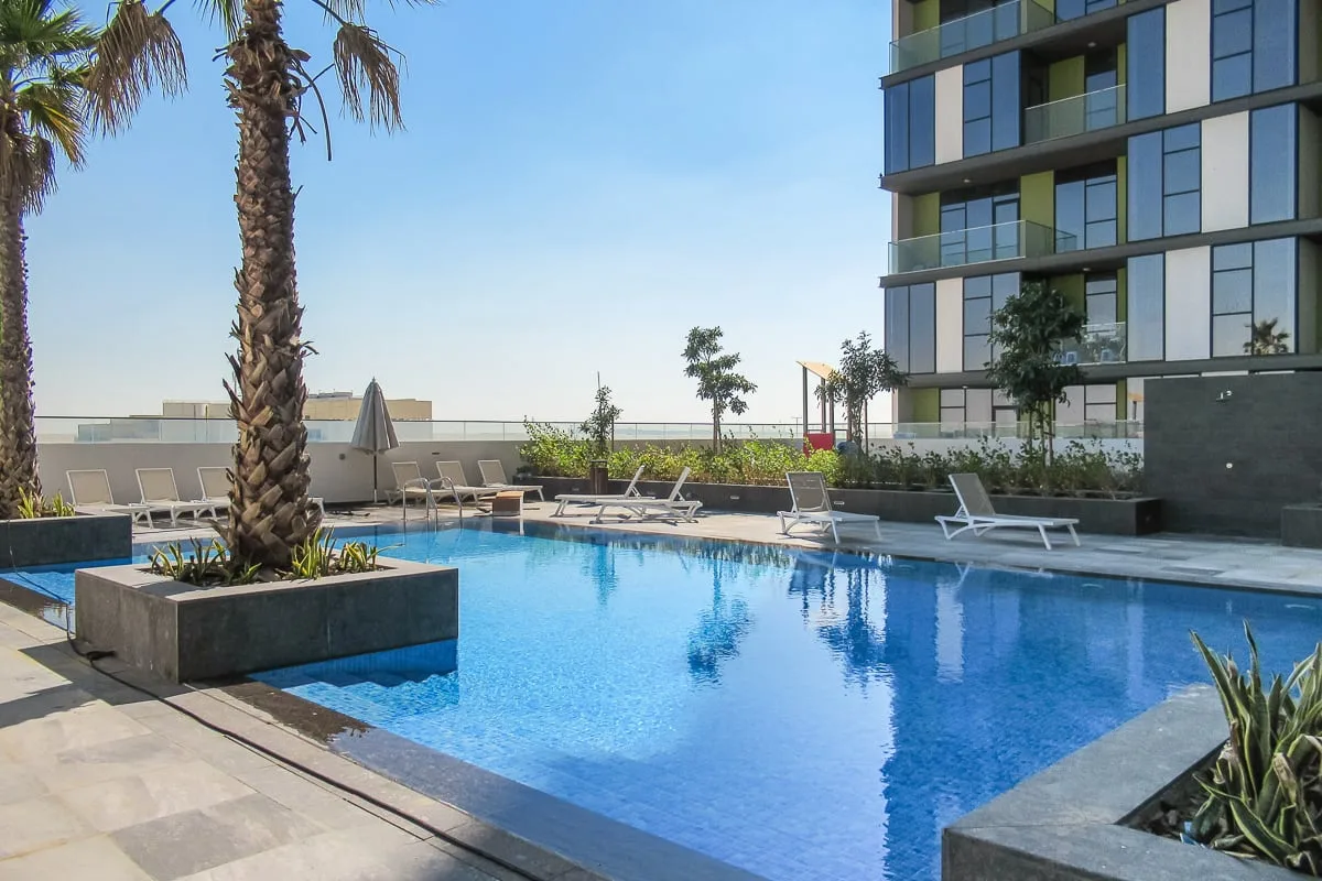 Una piscina en la azotea con asientos junto a un edificio moderno.