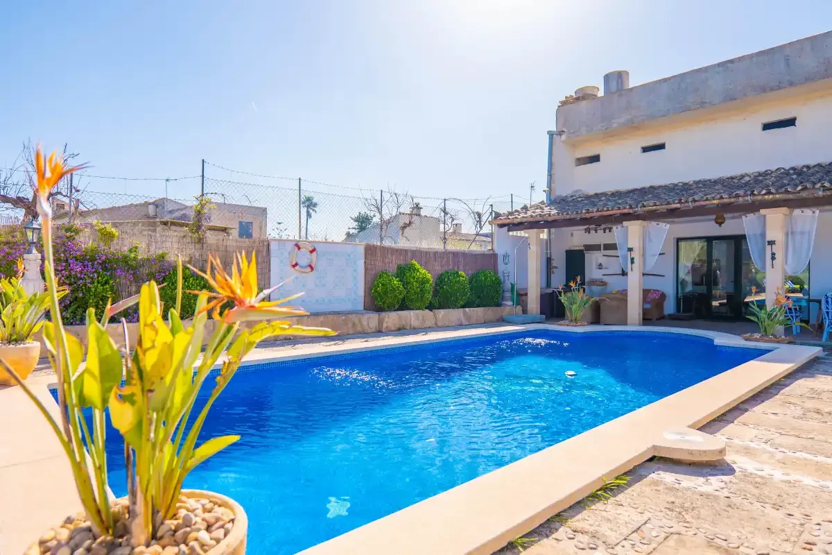 A swimming pool beside a patio and a building.