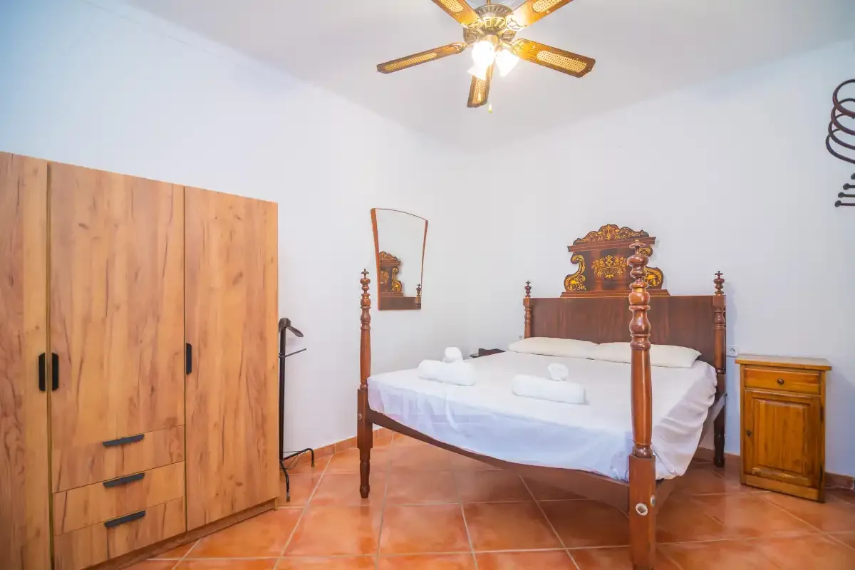 A bedroom with a wooden four-poster bed and wardrobe.