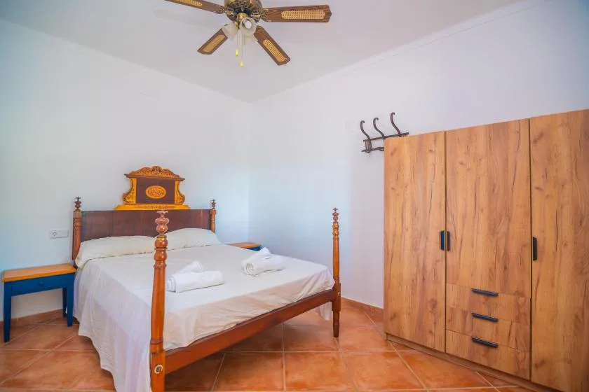 A bedroom with a wooden bed, white bedding, and a large wooden wardrobe.