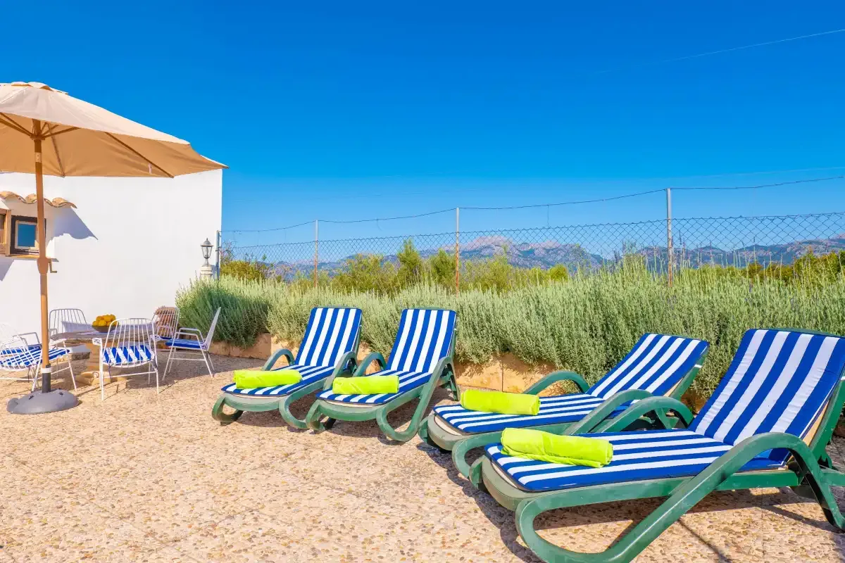 A sunny outdoor seating area with striped loungers beside a white building.