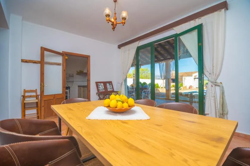 A dining room with a large wooden table set in front of glass doors.