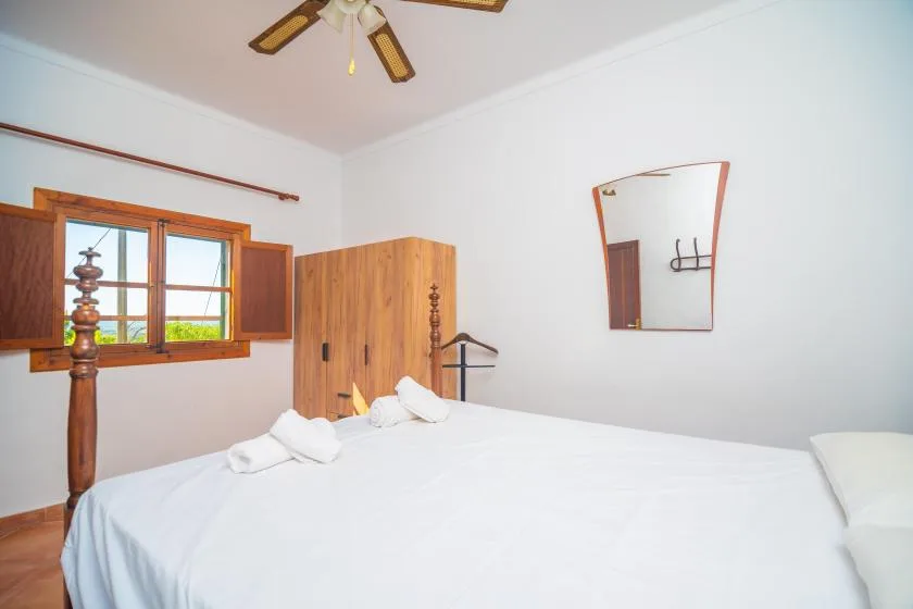 A bedroom with a large bed, wooden wardrobe, and window.