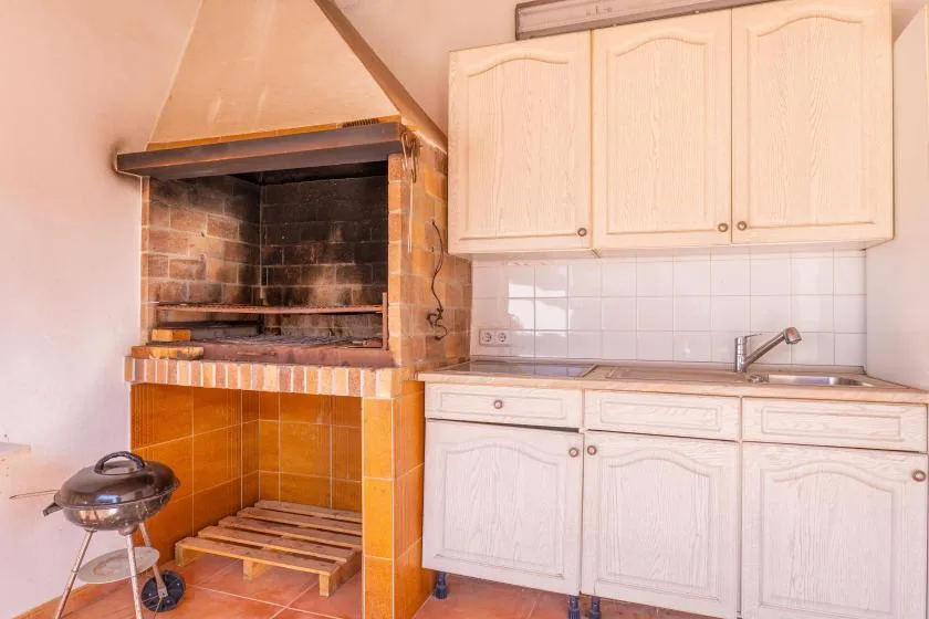 A kitchen with white cabinets and a built-in brick barbecue.