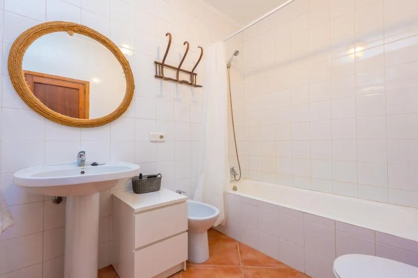 A tiled bathroom with a sink, mirror, and bathtub.