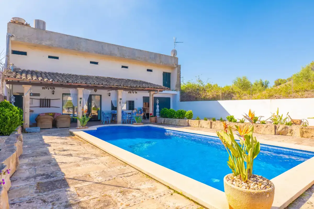 A swimming pool beside a two-story house with a covered patio.