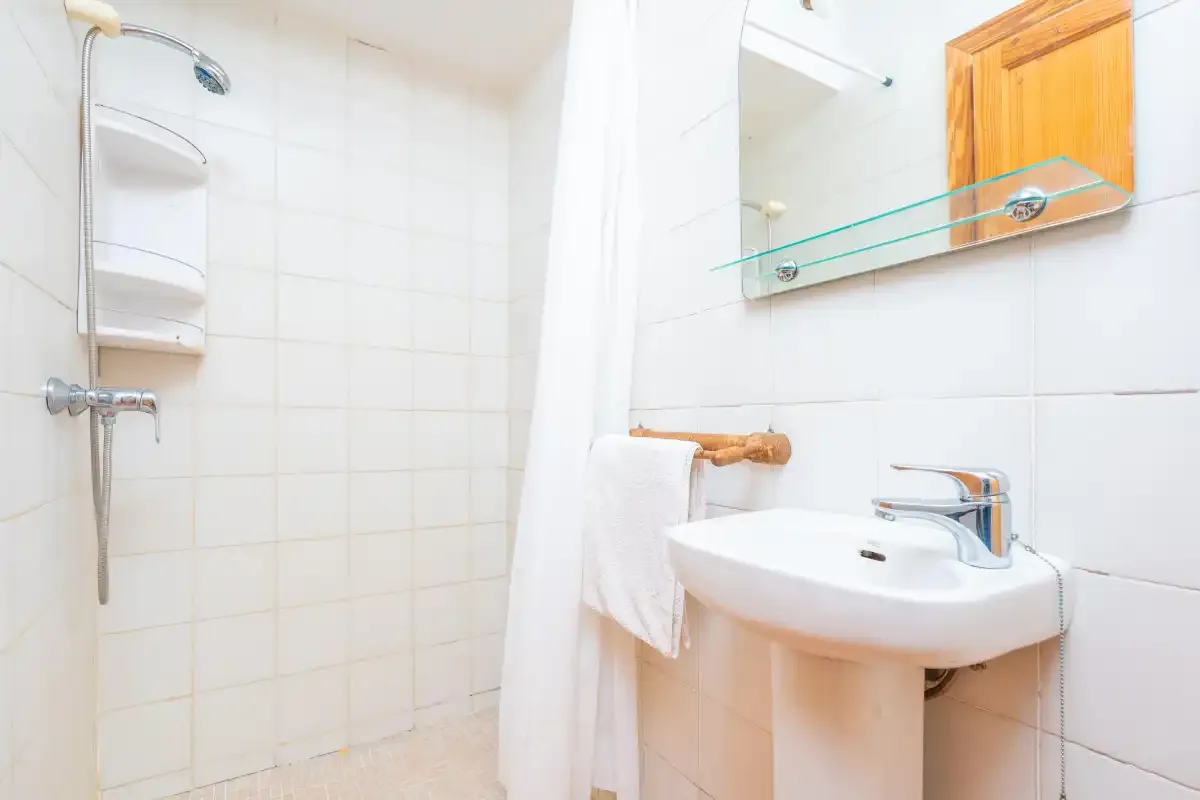A tiled bathroom with a shower, sink, and mirrored cabinet.
