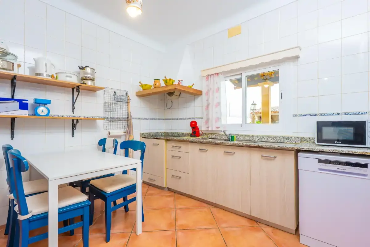 A tiled kitchen with a dining table and cabinets beneath the window.