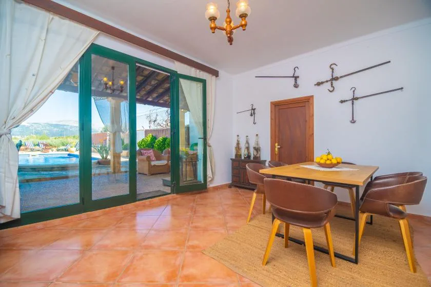 A dining area with a wooden table and chairs beside glass doors opening onto a patio.
