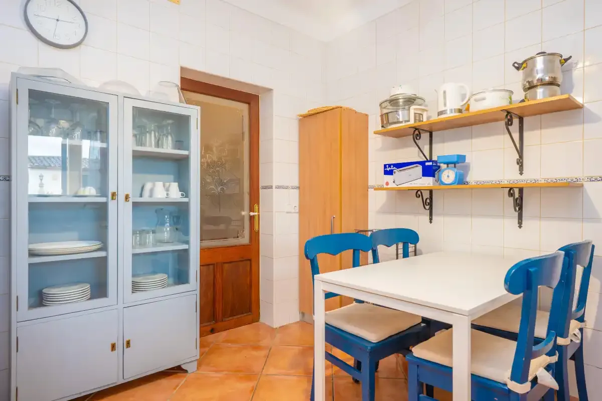 A tiled dining area with a white table, blue chairs, and storage cabinets.