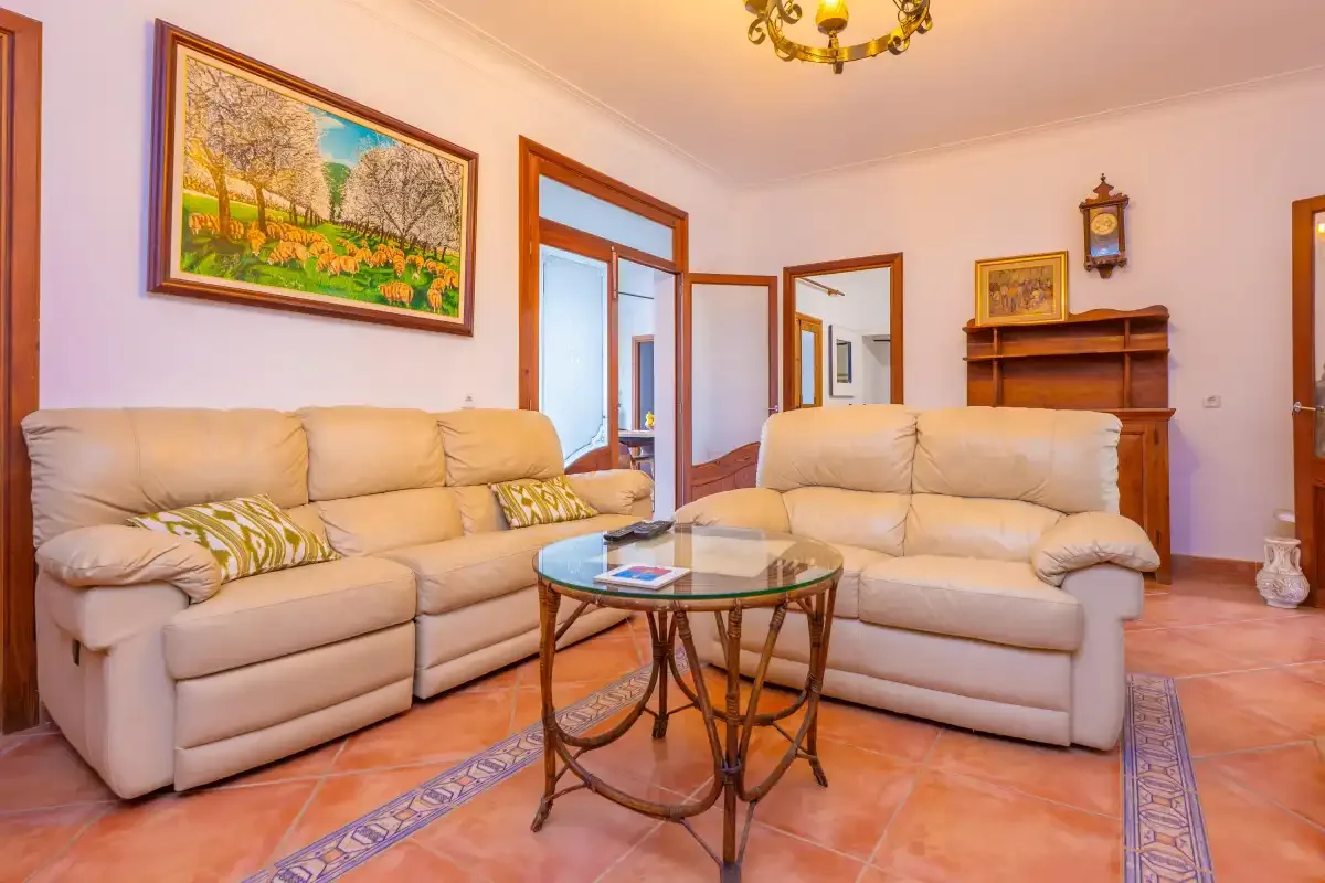 A living room with pale seating arranged around a glass coffee table.